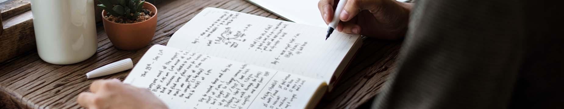 A woman focused on writing in a notebook, capturing her thoughts with a pen in a serene environment.
