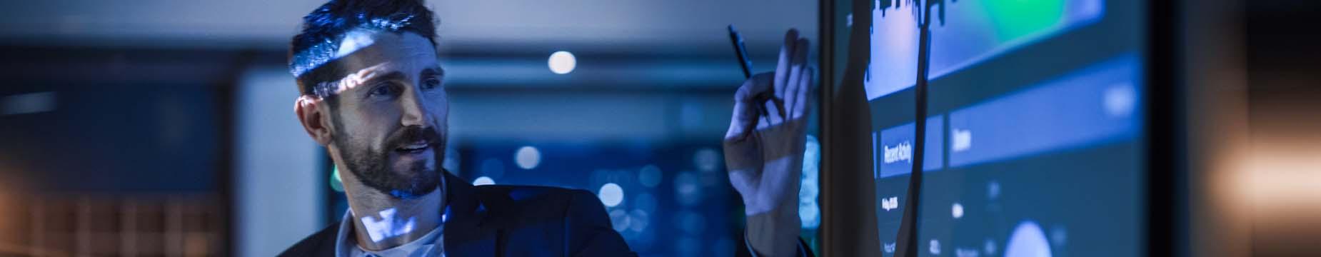 A man with a headset is focused, holding a pen in his right hand, ready to take notes or engage in a conversation.