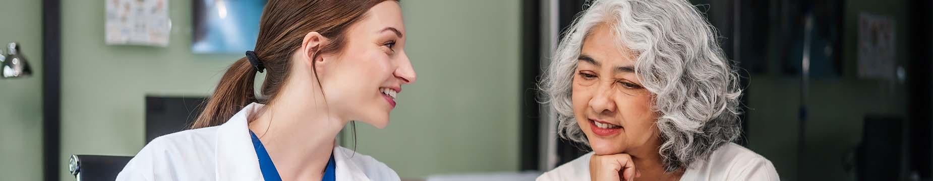A doctor and patient engaged in a conversation at a desk, discussing health matters in a professional setting.