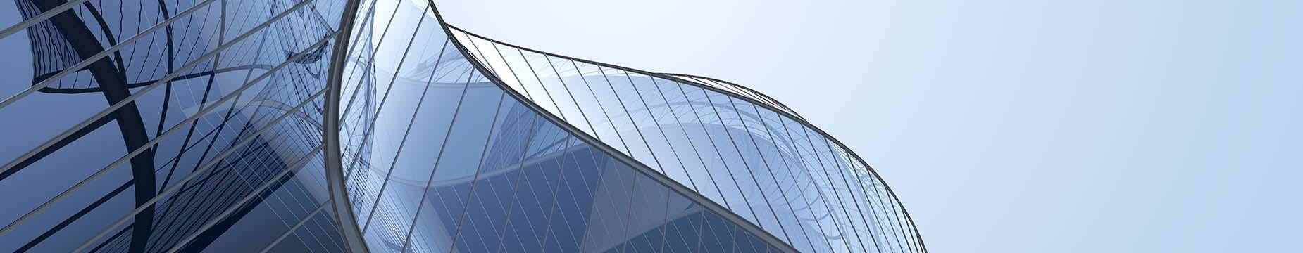 A contemporary building featuring sleek, curved glass walls that reflect the surrounding environment.