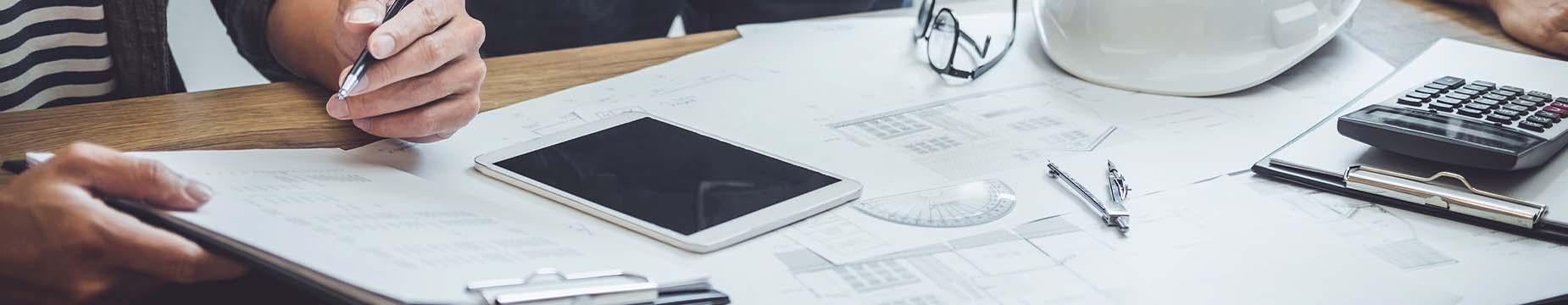 A person focused on a project, using a laptop and a pen to take notes and organize their ideas.