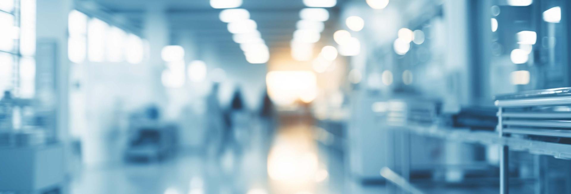 A blurred hallway scene featuring individuals walking, creating a sense of movement and depth in the space.