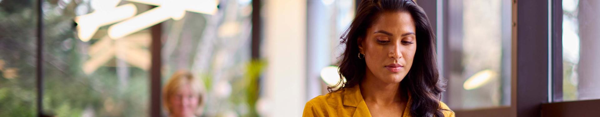 A woman focused on her laptop, working diligently in a modern office environment.