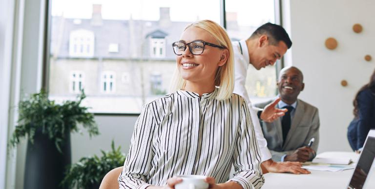 A woman with glasses sits at a table alongside two men, actively involved in a dialogue and exchanging thoughts.