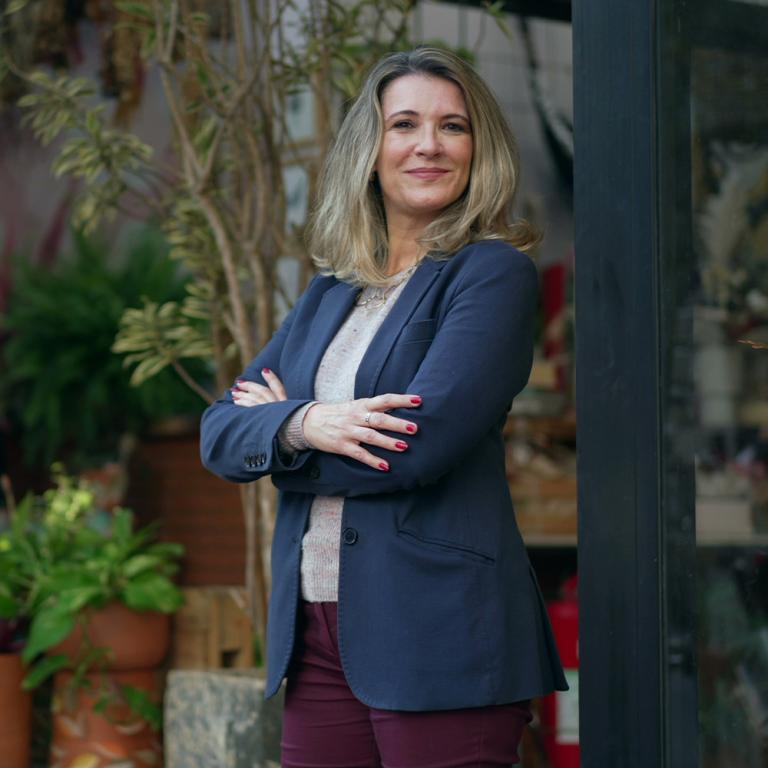 A female MBA student stands outside with a thoughtful expression on her face