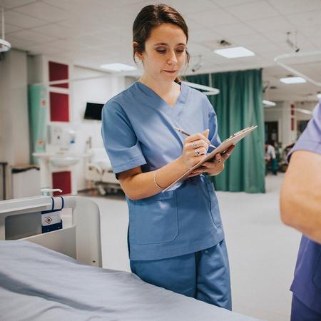 A nurse assists a patient in a hospital room, providing care and support in a clinical environment.