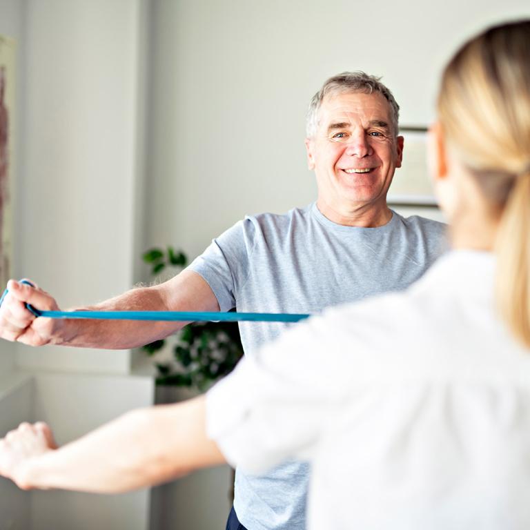 A man performs exercises in the foreground, while another man is visible in the background, observing the activity.