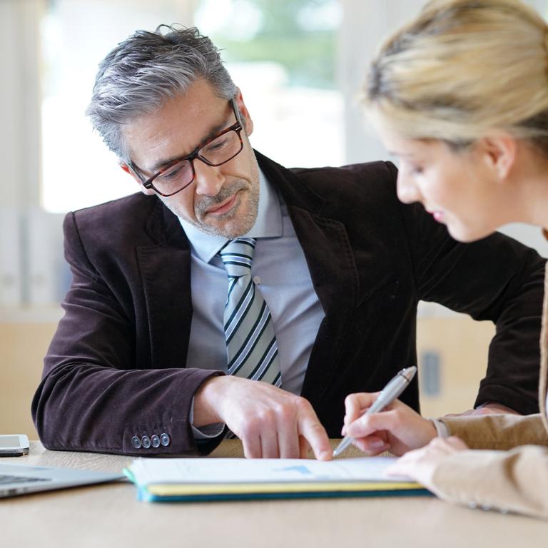 A man and woman are intently examining a document together, discussing its contents with focused expressions.