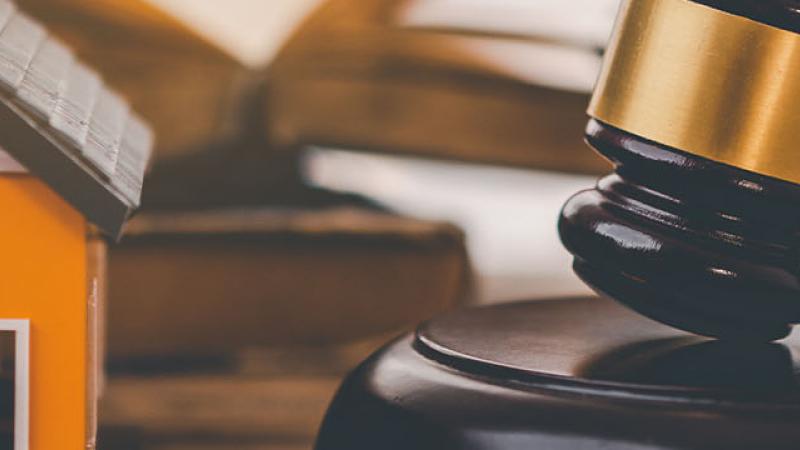 A gavel rests beside a house model on a table, symbolising the intersection of law and real estate.