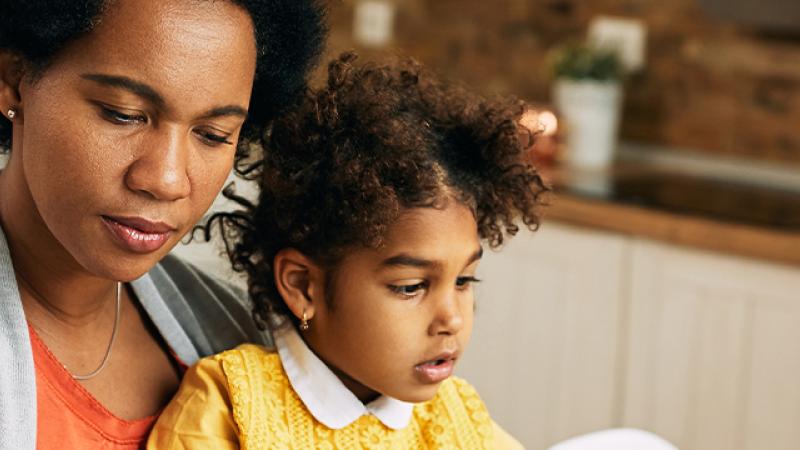 A woman and a child collaboratively working on a laptop, engaged in a productive learning experience together.