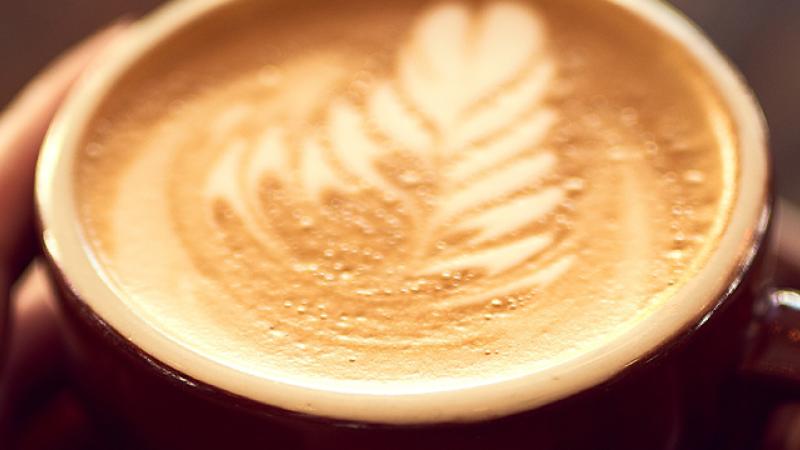 A woman's hands gently cradle a steaming cup of coffee, showcasing warmth and comfort in a cozy setting.