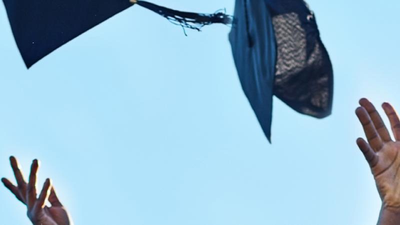 Graduates joyfully tossing their caps into the air, celebrating their academic achievements in a moment of triumph.