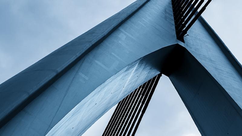 A close-up view of a bridge against a clear blue sky, showcasing its structure and the vibrant atmosphere.