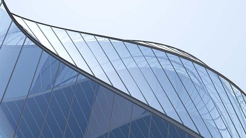 A contemporary building featuring sleek, curved glass walls that reflect the surrounding environment.