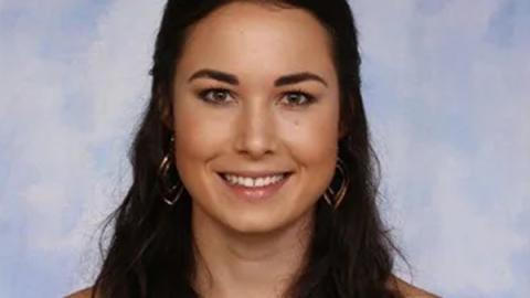 A woman with long dark hair wearing a gold hoop earring, exuding elegance and style in her appearance.