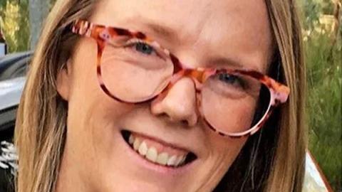 A smiling woman wearing glasses poses for the camera, exuding warmth and friendliness.