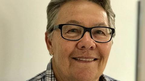 A smiling woman wearing glasses and a plaid shirt, exuding a friendly and approachable demeanor.