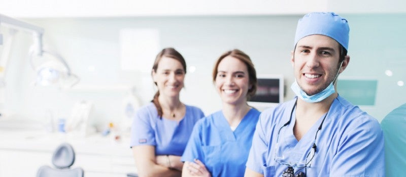 A doctor and two nurses standing together in a hospital room.