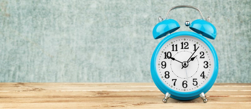 A blue alarm clock on a wooden surface.