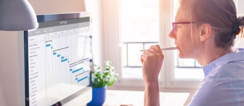 A female professional holding a pen and focusing on a screen showing data. 