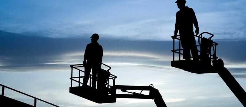 A silhouette of two engineers on cranes.  